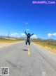 A person jumping in the air on the side of a road.