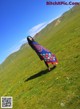 A woman in a colorful dress standing in a grassy field.