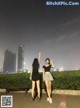 A couple of women standing next to each other on a sidewalk.