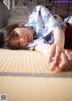 A young girl laying on a tatami mat in a room.