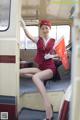 A woman in a red uniform is sitting on a train.