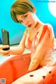 A woman in a bathtub with blood on her body taking a selfie.