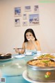 A woman sitting at a table eating food with chopsticks.