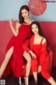 A couple of women sitting on top of a red couch.