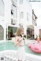 A woman standing next to a pool with a pink flamingo float.