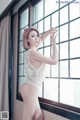 A woman in a white lingerie leaning against a window.