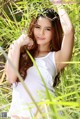 A woman in a white tank top posing in a bamboo forest.