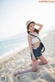 A woman in a straw hat is sitting on the beach.