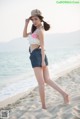 A woman standing on a beach next to the ocean.