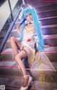 A woman with long blue hair sitting on a set of stairs.