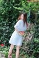 A woman in a blue and white striped dress holding a watermelon.