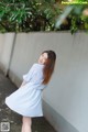 A woman in a blue and white striped dress leaning against a wall.