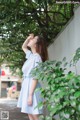 A woman in a blue and white striped dress leaning against a wall.