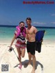 A man and a woman standing on a beach with snorkeling gear.