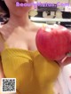 A woman in a yellow dress holding an apple.