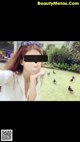 A woman taking a selfie with a group of birds in the background.