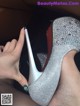 A woman's hand holding a pair of silver high heels.