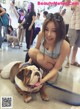 A woman kneeling down next to a bulldog on a leash.