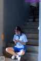 A woman sitting on the steps of a building looking at her phone.