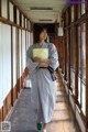 A woman in a black and white kimono standing in a hallway.