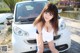 A woman posing in front of a white car.