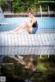 A woman sitting on the edge of a swimming pool.