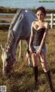 A woman standing next to a white horse in a field.