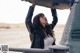 A woman in a black leather jacket standing next to a car.