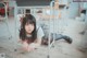 A young girl laying on the floor under a desk.