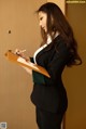 A woman in a business suit writing on a clipboard.