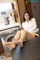 A woman sitting on top of a table next to a washing machine.