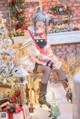 A woman sitting on a chair in front of a Christmas tree.