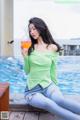 A woman sitting by a pool holding a glass of orange juice.