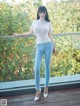 A woman in a white top and blue jeans posing for a picture.