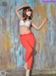 A woman in a white bra top and red pants posing for a picture.